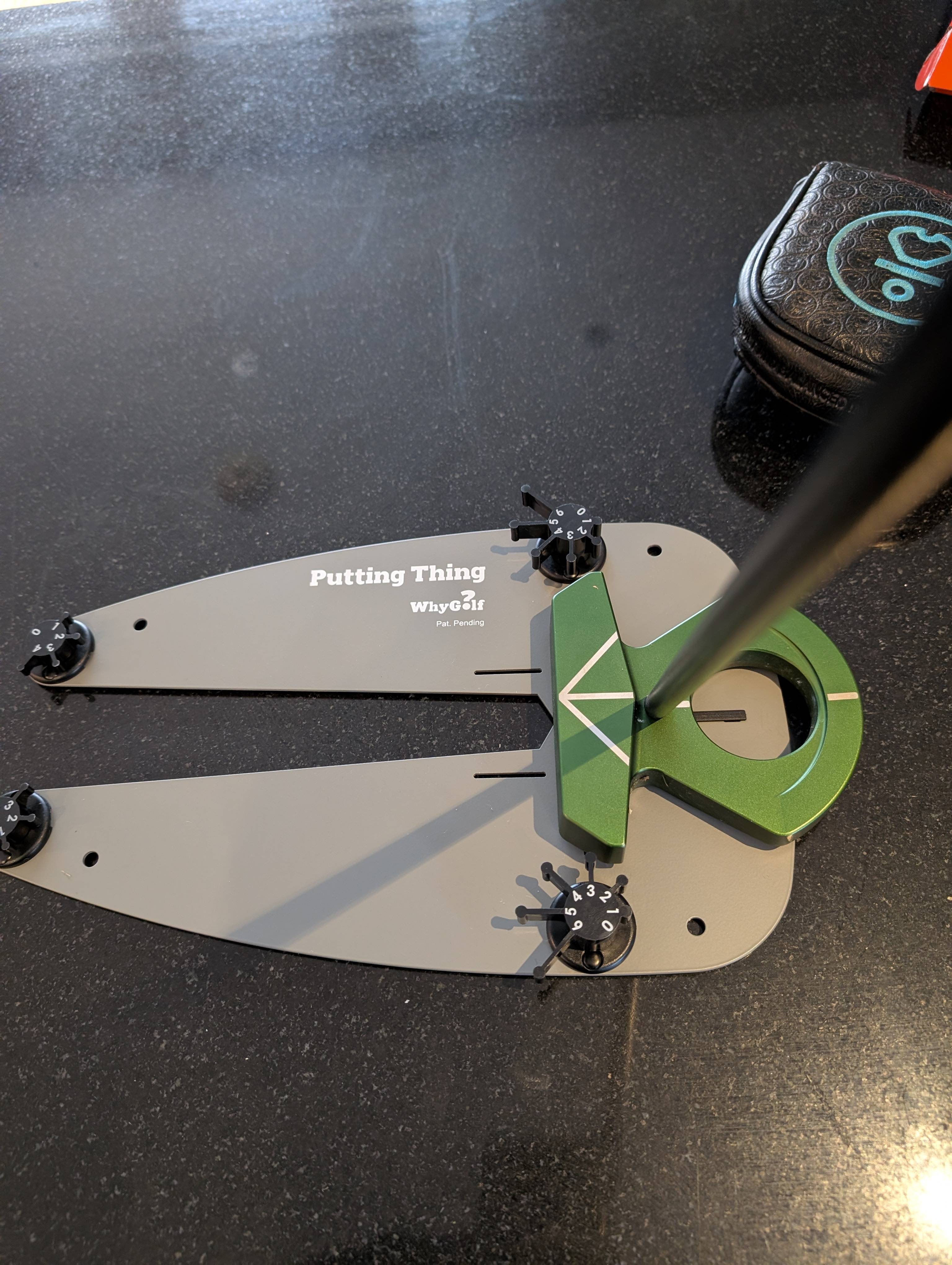 The Putting Thing set up on a putting surface with putter and golf ball.